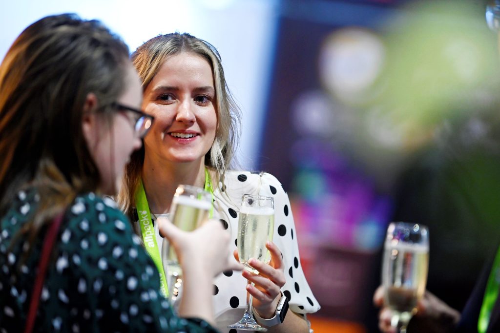 Two female leaders in packaging talking at event.