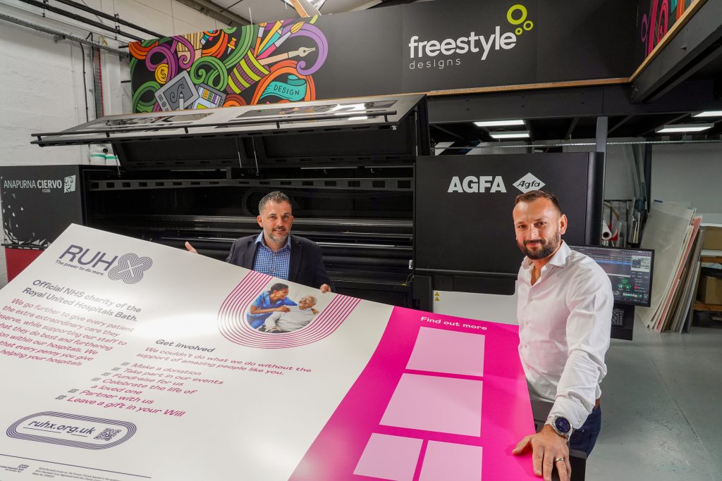 Two men holding large format print banner from Anapurna Ciervo H3200 printer